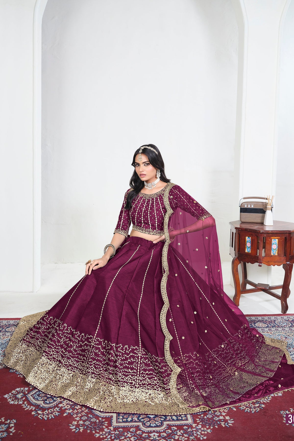 Alternate view of a wine purple lehenga skirt with mirror work on the lehenga skirt, seated pose, full outfit visible. All-over mirror work.