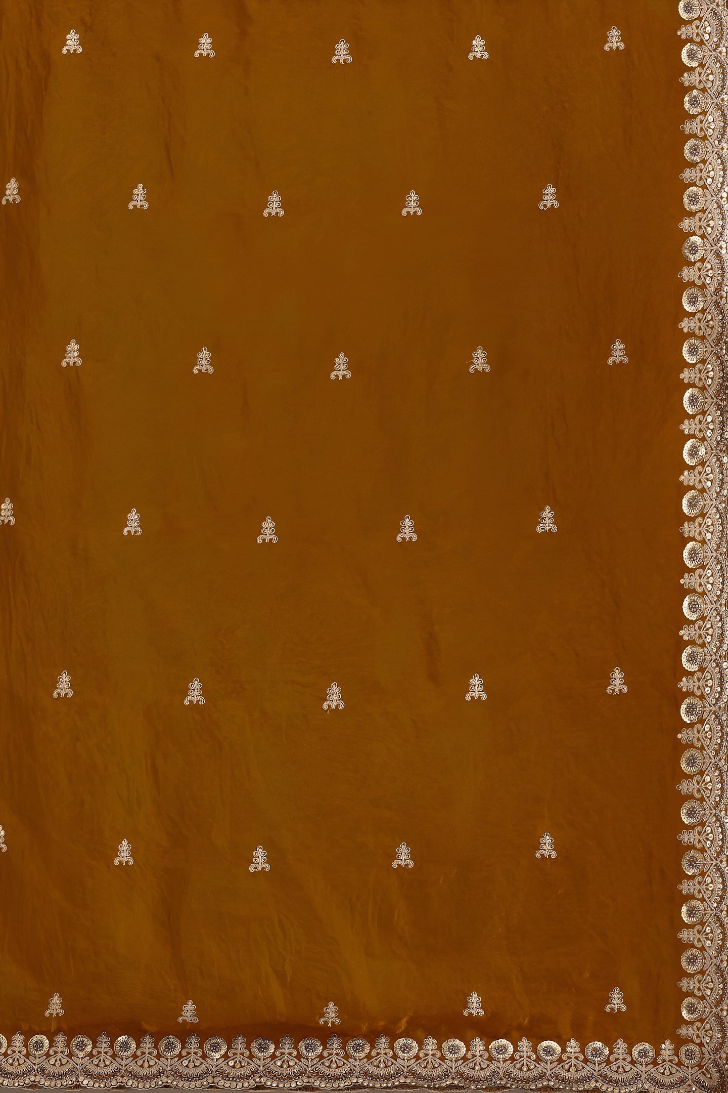 Brown fabric with white embroidered patterns and a decorative border.