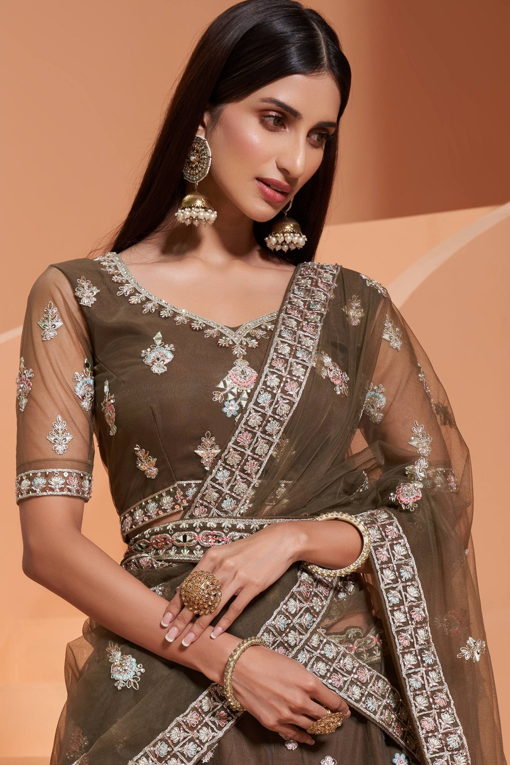 Close-up of the olive green V neck blouse with sheer sleeves, mirror and thread embroidery, worn with jhumka earrings — festive wear for women in rich olive tones.