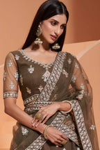 Close-up of the olive green V neck blouse with sheer sleeves, mirror and thread embroidery, worn with jhumka earrings — festive wear for women in rich olive tones.