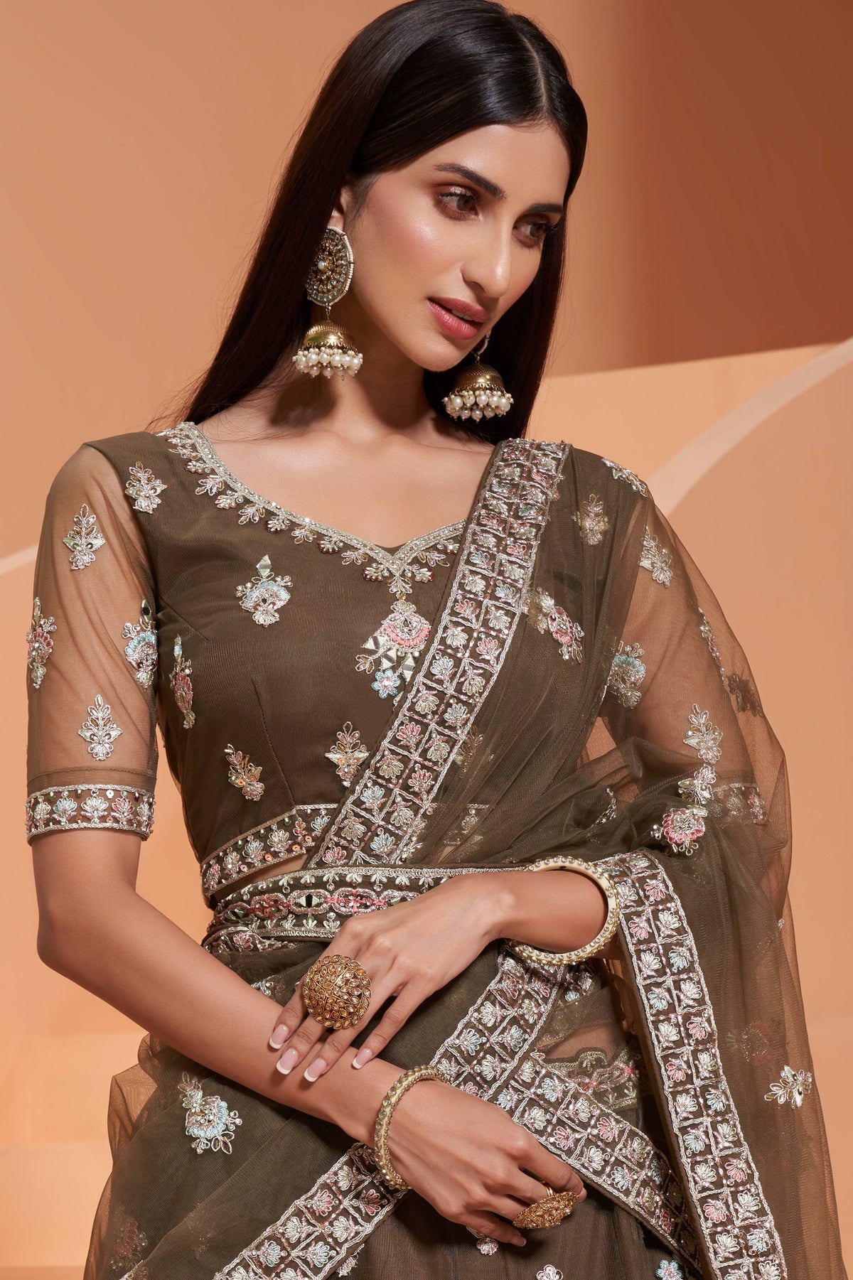 Close-up of the olive green V neck blouse with sheer sleeves, mirror and thread embroidery, worn with jhumka earrings — festive wear for women in rich olive tones.