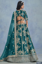 A back view of a woman in a Teal blue embroidered lehenga choli for reception shows the open-back blouse, embroidered skirt and net dupatta.