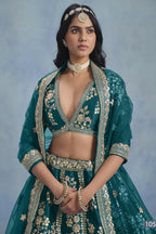 A waist-up front view shows a woman in a Teal blue embroidered lehenga choli for reception with a V-neck embroidered blouse and net dupatta.