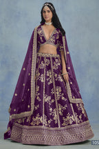 A woman in a full-length front view wears a purple embroidered lehenga choli for reception with floral work and net dupatta on a blue studio backdrop.