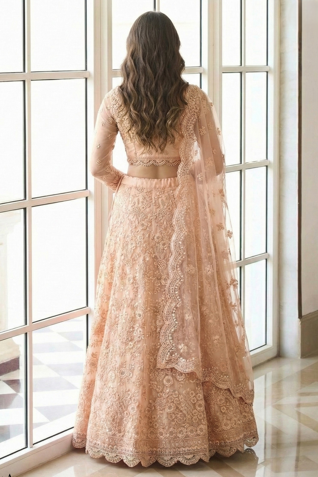 Back view of the peach lehenga choli with open back blouse, sheer embroidered sleeves and scalloped dupatta — an elegant long sleeve lehenga in soft peach net.