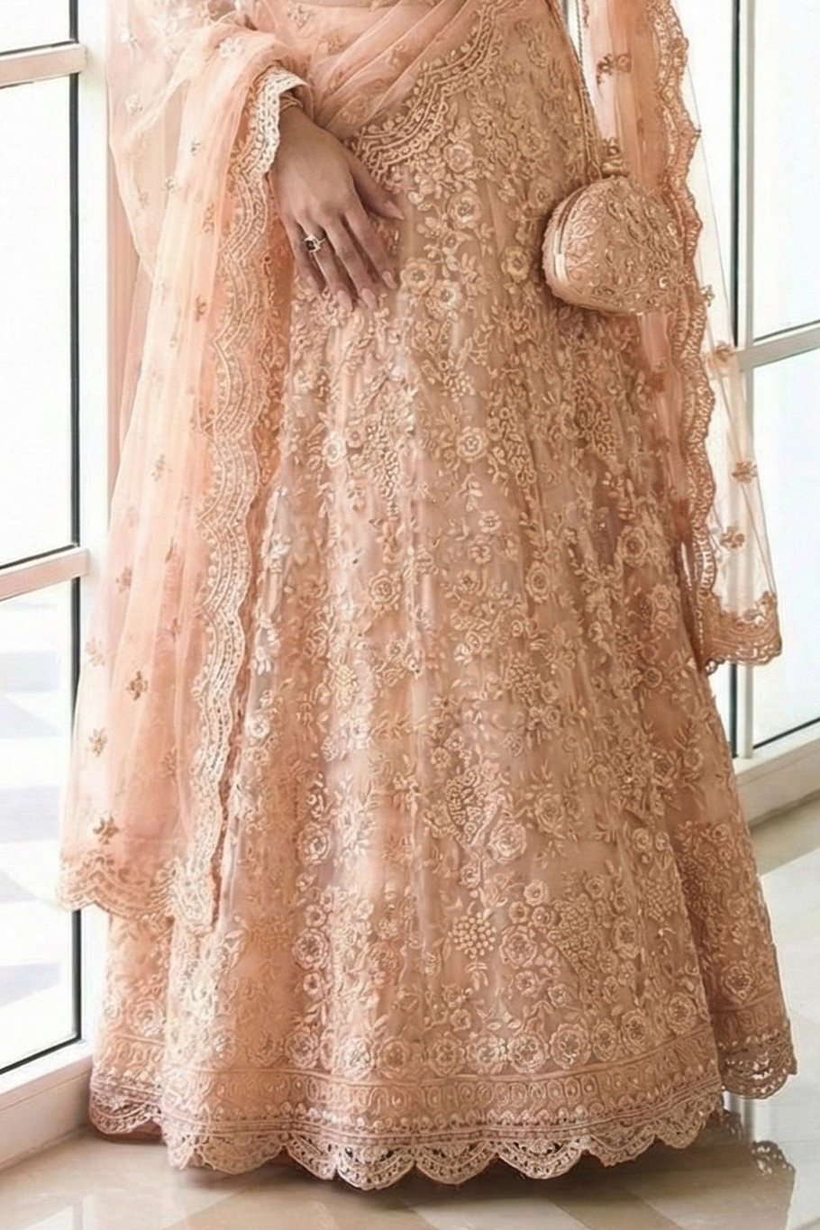 Waist-down close-up of the peach lehenga showing dense floral embroidery, scalloped dupatta border and potli bag — a dreamy engagement lehenga with stone and thread work.