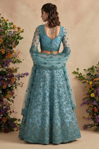 Back view of the teal blouse with open back and dori ties, sheer embroidered sleeves and flared skirt — a detailed indian lehenga choli for wedding celebrations.