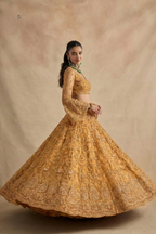 Twirl view of the golden lehenga showing the flared embroidered skirt and open back blouse — festive sangeet outfits in shimmering gold net with stone work.