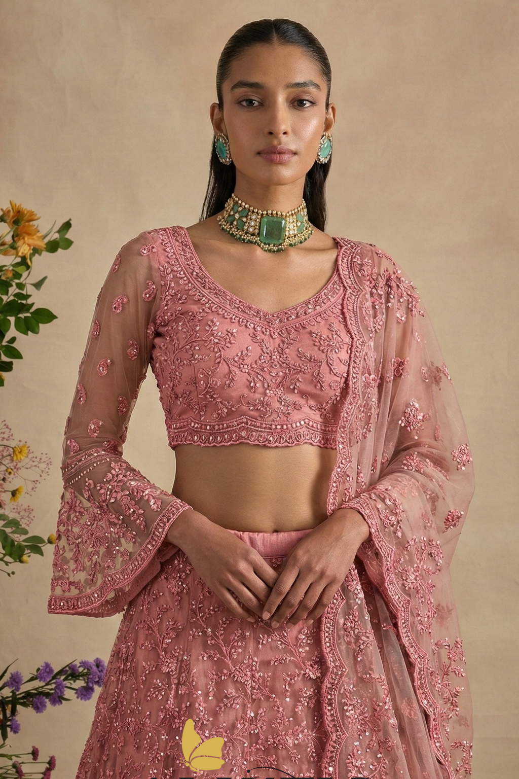 Close-up of the dusty pink V neck blouse with sheer bell sleeves in floral thread embroidery — beautiful lehengas for wedding guest looks with stone detailing.