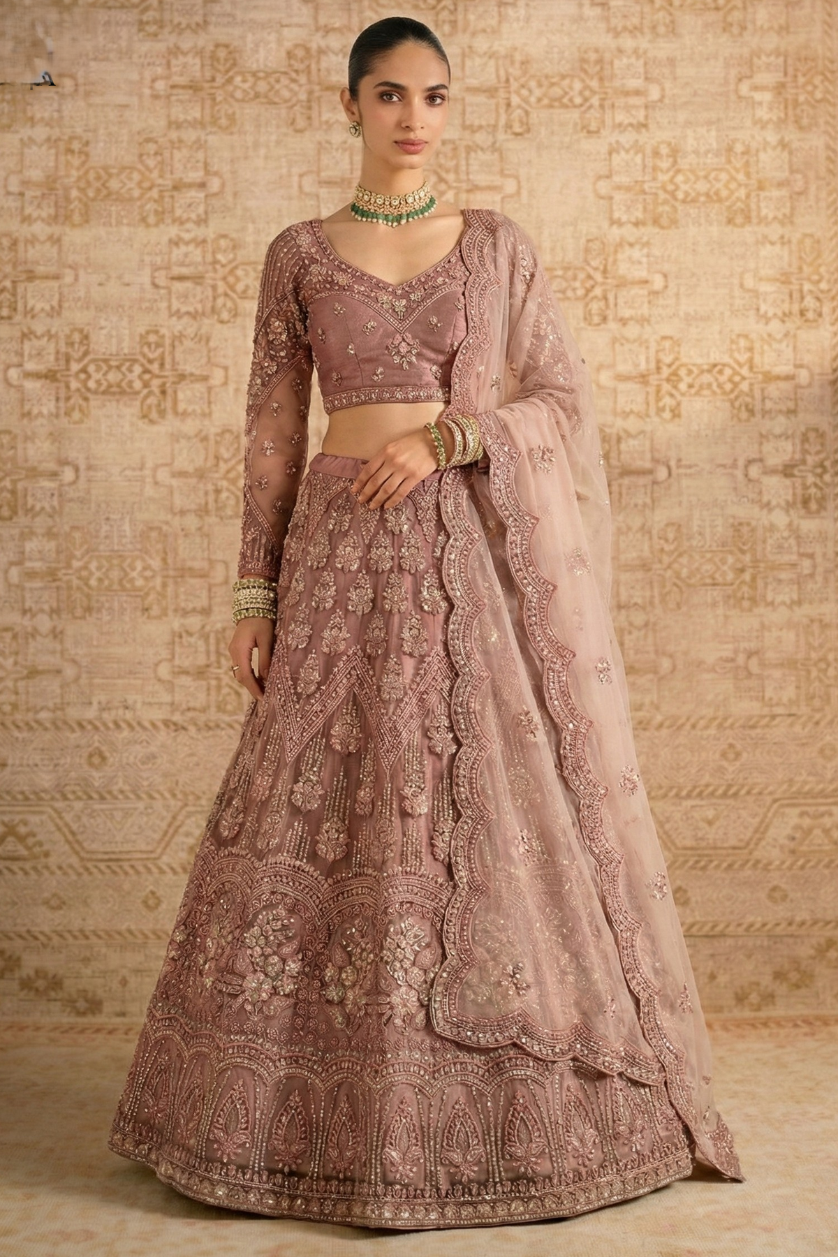 Model in a mauve net lehenga choli with long sheer embroidered sleeves, V neckline and scalloped dupatta — elegant long sleeve lehengas for wedding guest looks.