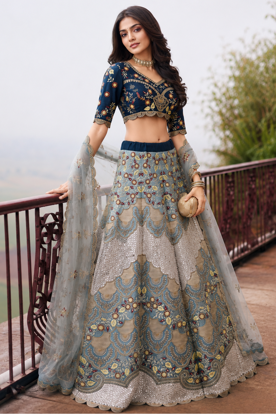 front standing view of a navy blue silk lehenga choli with embroidered silk lehenga skirt and net dupatta drape. All-over embroidery.