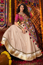 Woman in traditional attire standing in a decorated room with colorful decorations and patterns.