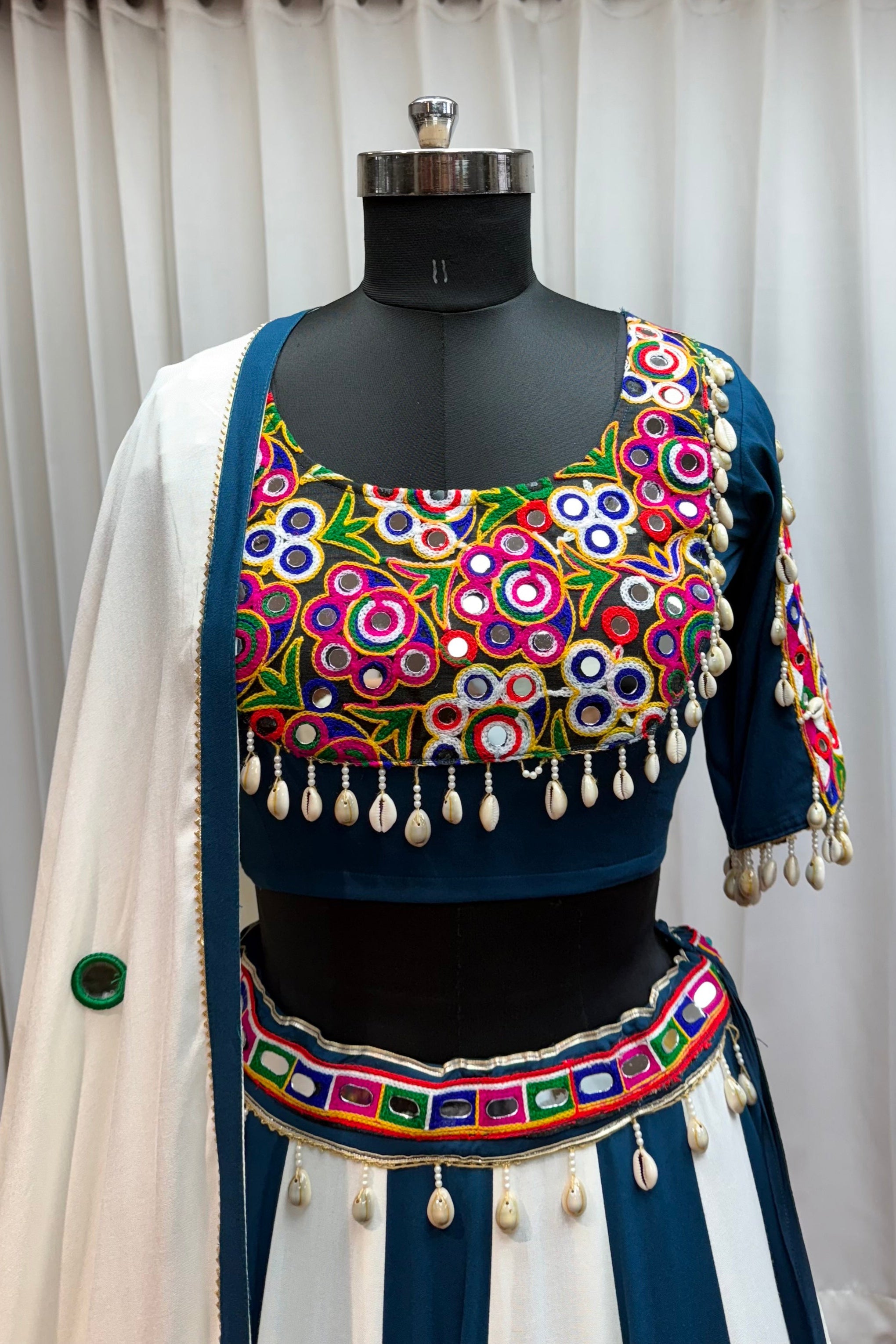 Colorful embroidered traditional outfit on a mannequin against a white curtain background