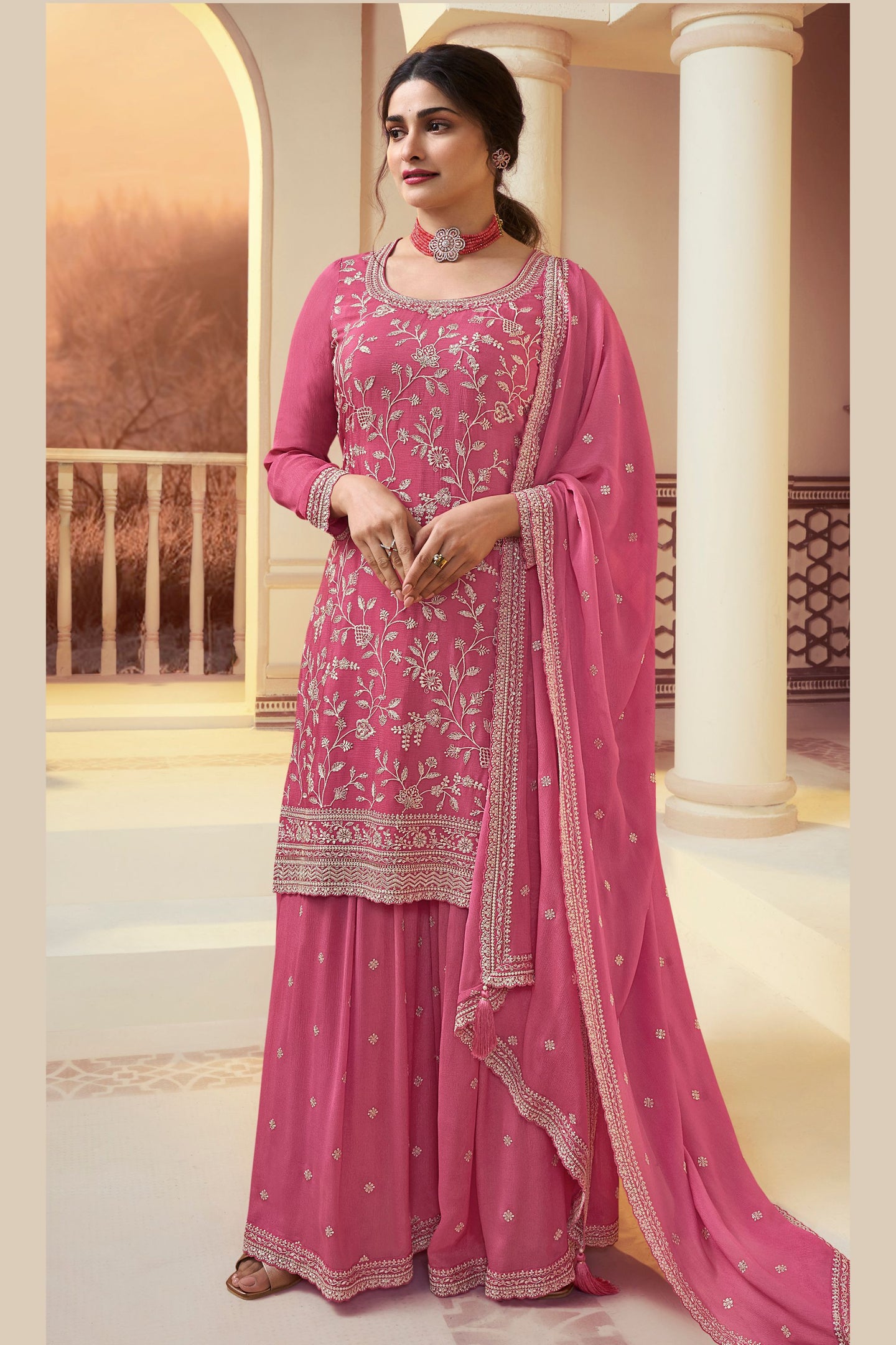 A woman wearing a traditional pink Chinon silk palazzo suit with embroidery work, consisting of a kameez, plazo, and dupatta, suitable for Indian festivals and Pakistani weddings.