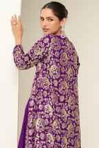 A back three-quarter view of a woman wearing a purple party wear outfit showing the embroidered long jacket back.