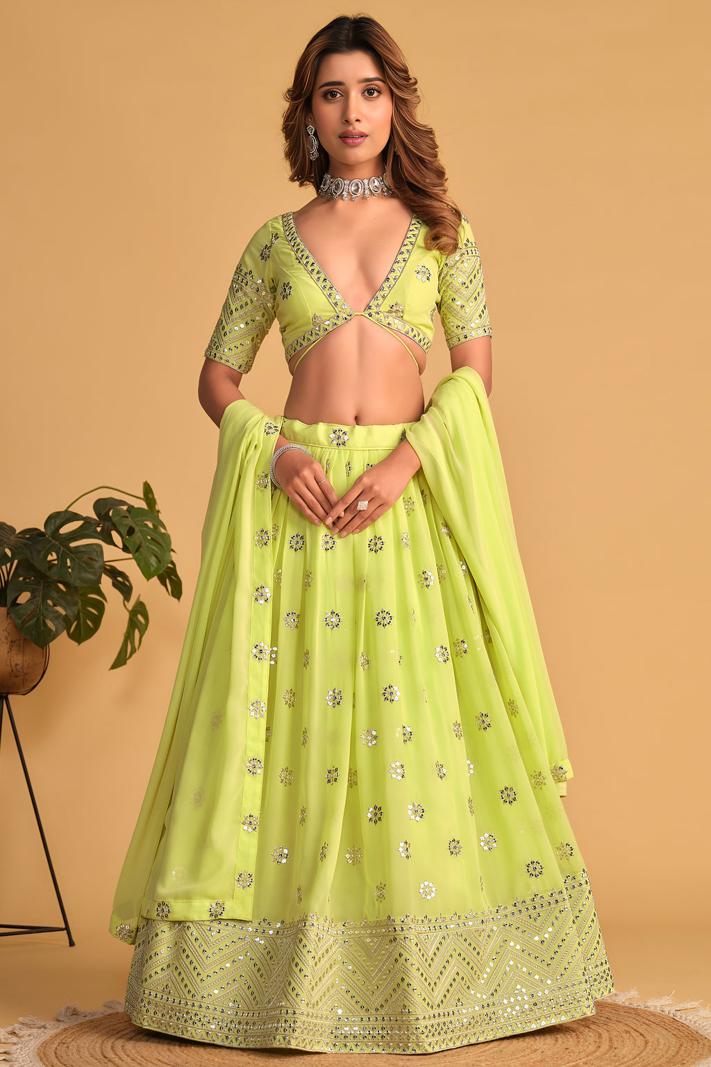Woman wearing a neon yellow party wear lehenga with zari and sequin embroidery, half sleeve V neck choli, full-length front view.
