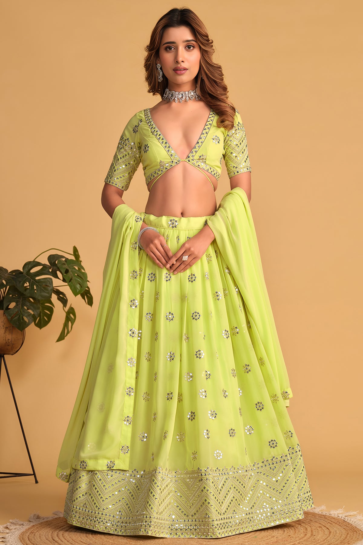 Woman wearing a neon yellow party wear lehenga with zari and sequin embroidery, half sleeve V neck choli, full-length front view.
