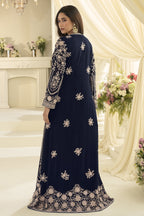 A rear-view portrait shows a woman in a navy blue embroidered ladies anarkali suit posing beside cream drapes and floral arrangements.
