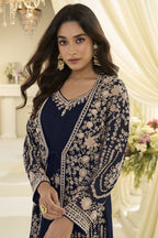 Close-up portrait of a woman posing indoors in one of the navy blue anarkali dresses for women, featuring intricate gold floral embroidery and ornate jewelry.