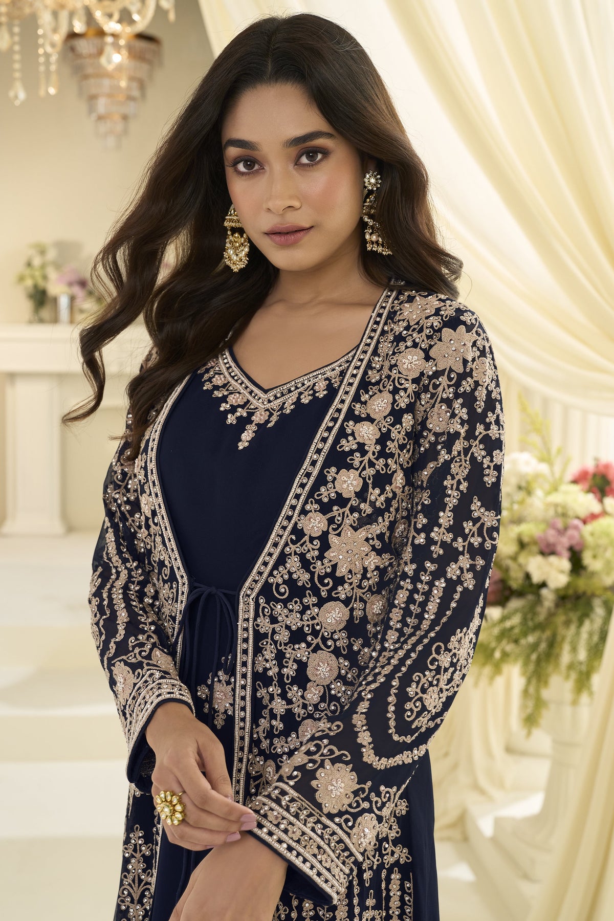 Close-up portrait of a woman posing indoors in one of the navy blue anarkali dresses for women, featuring intricate gold floral embroidery and ornate jewelry.