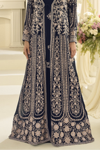 A navy blue floor-length anarkali with extensive embroidery, shown on a model in an elegant indoor setting.