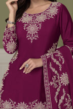 A woman modeling a Burgundy ethnic kurta with intricate embroidery, paired with a matching embroidered dupatta, set against a muted olive green background.