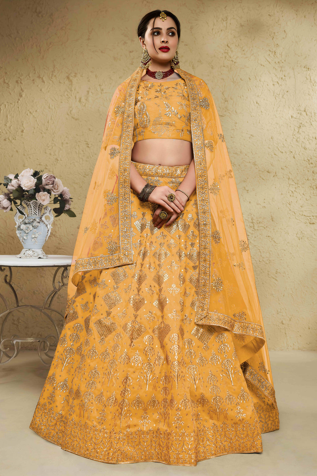 Woman wearing a mustard yellow haldi outfits lehenga in art silk with zari and sequin embroidery, half sleeve boat neck blouse, full-length front view.