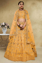 Woman wearing a mustard yellow haldi outfits lehenga in art silk with zari and sequin embroidery, half sleeve boat neck blouse, full-length front view.