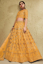 Full-length side view of a mustard yellow reception lehenga in art silk with zari and sequin embroidery work on the flared lehenga skirt.