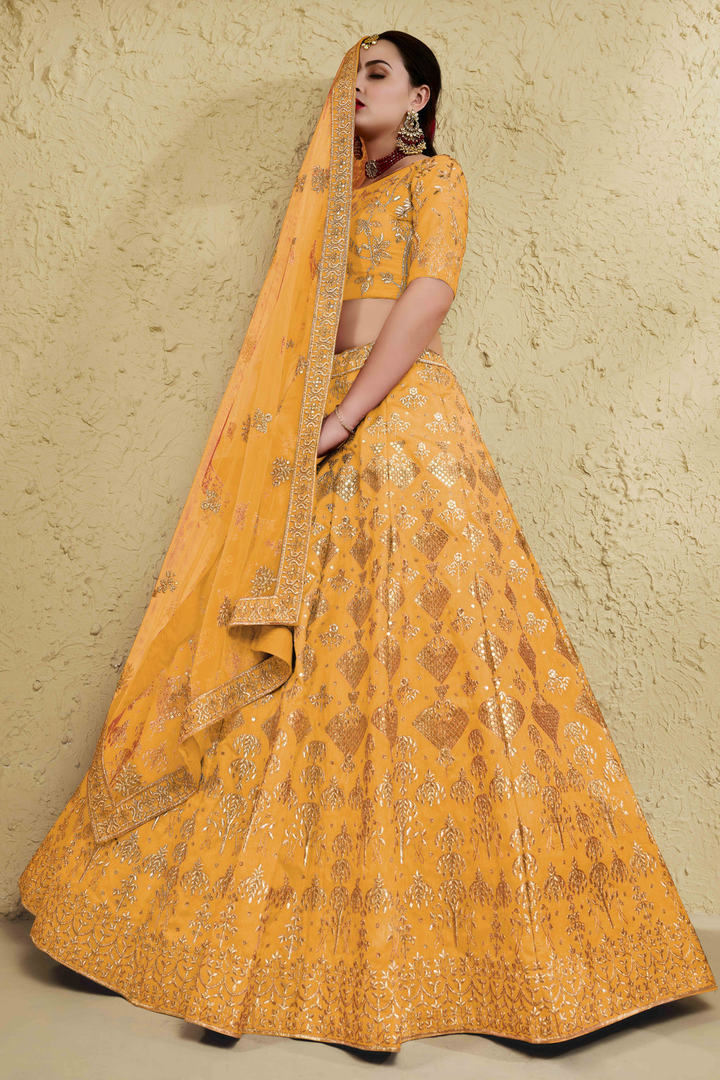 Alternate full-length view of a mustard yellow haldi outfits lehenga in art silk with zari and sequin embroidery work on the blouse and lehenga.