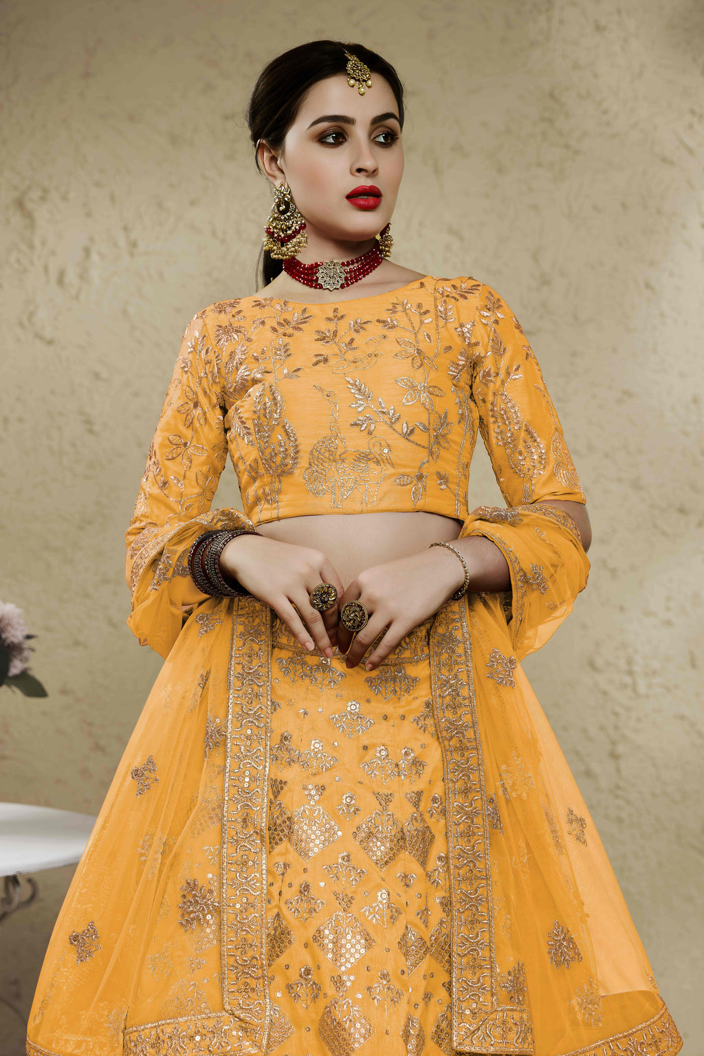 Close-up view of a mustard yellow haldi outfits lehenga in art silk with detailed zari and sequin embroidery work on the blouse and skirt.