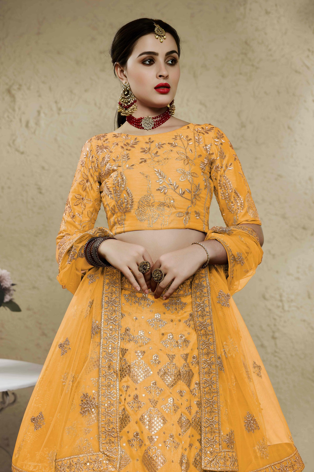 Close-up view of a mustard yellow haldi outfits lehenga in art silk with detailed zari and sequin embroidery work on the blouse and skirt.