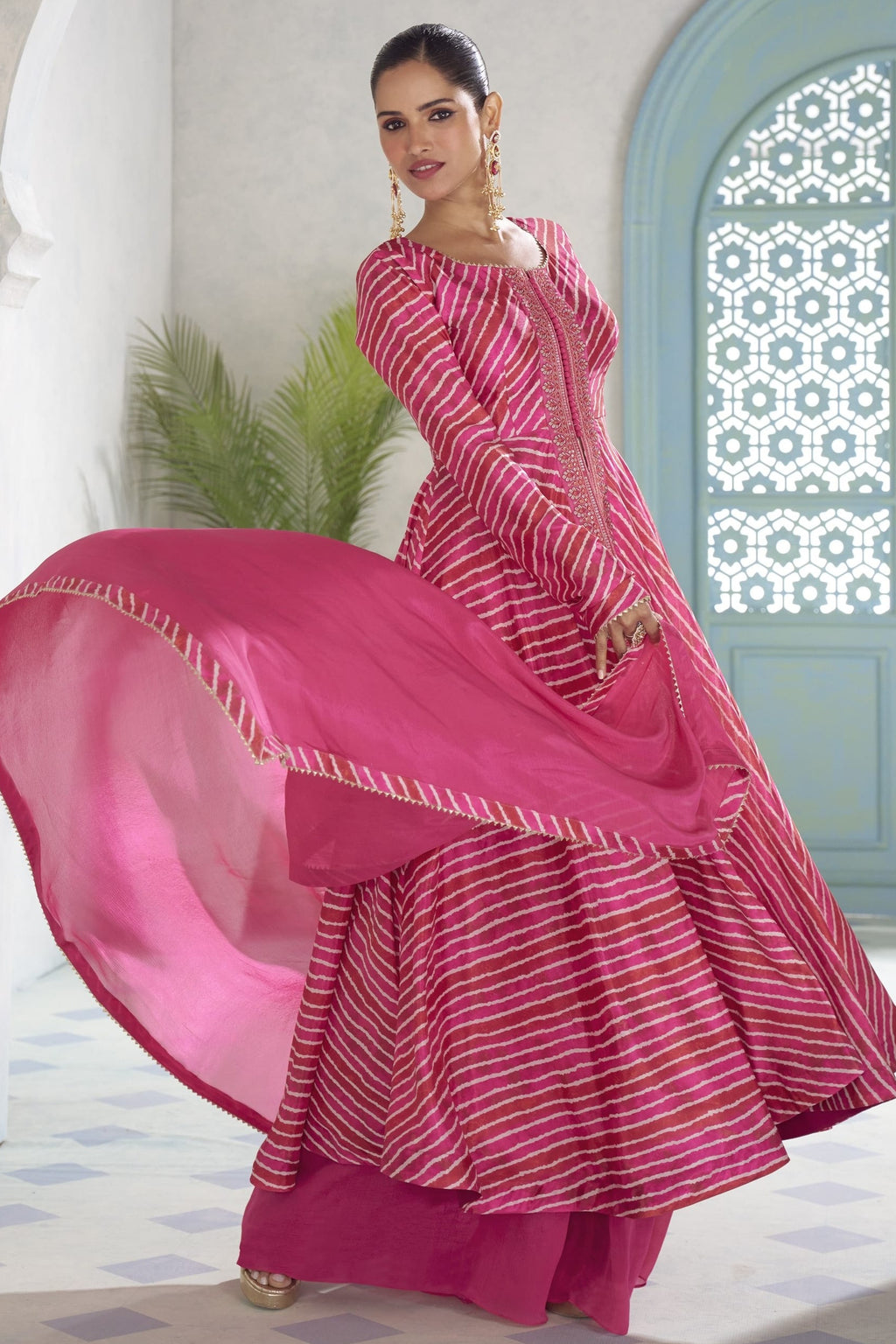 Model twirling in the fuchsia pink plazo suit, showing the flared kameez and matching dupatta.