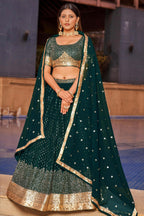 Woman wearing a green and gold traditional outfit with a matching dupatta.