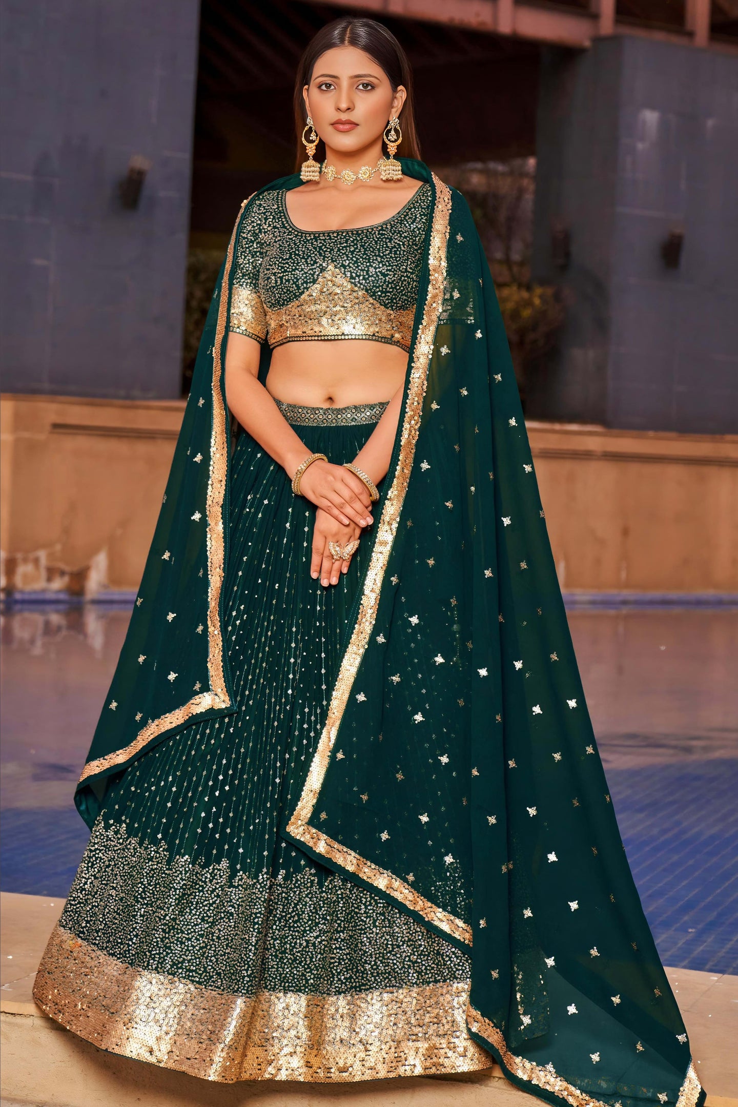 Woman wearing a green and gold traditional outfit with a matching dupatta.