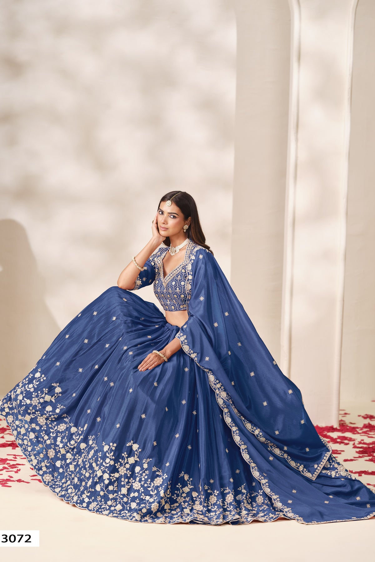 Full-length seated view of a dusty blue outfits for eid style lehenga in chinon silk with sequin and thread embroidery on the flared skirt.