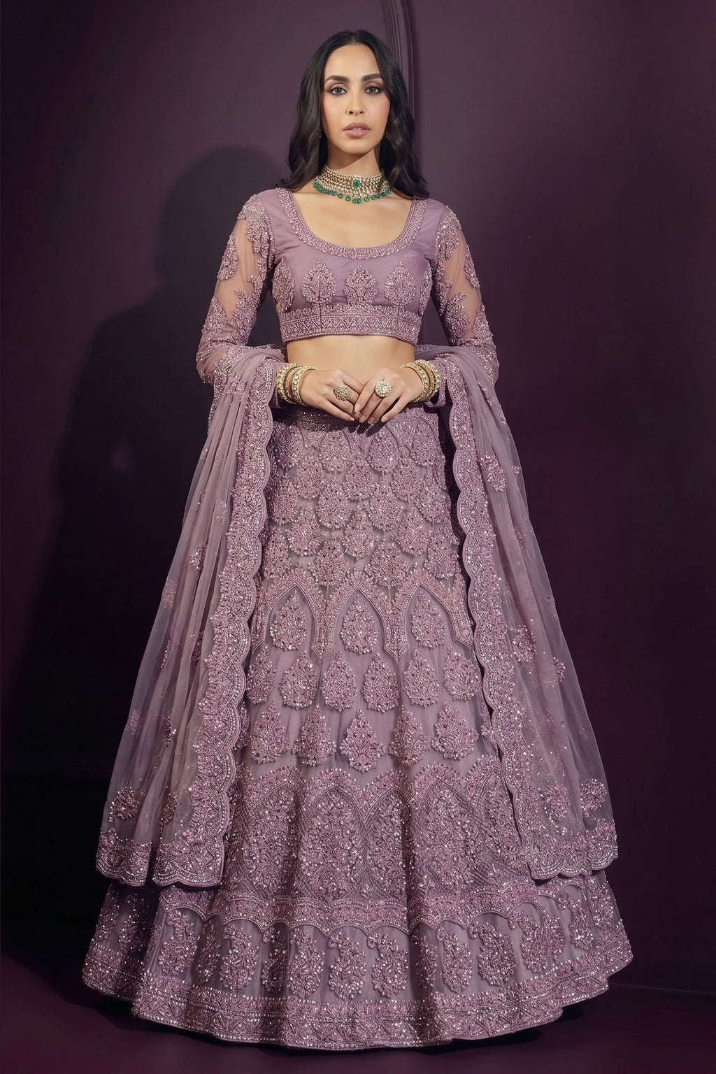 Front view of an indian lehenga choli in mauve net with hand-worked embroidery on the blouse and skirt, dupatta resting on the shoulder.