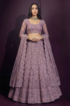 Front view of an indian lehenga choli in mauve net with hand-worked embroidery on the blouse and skirt, dupatta resting on the shoulder.