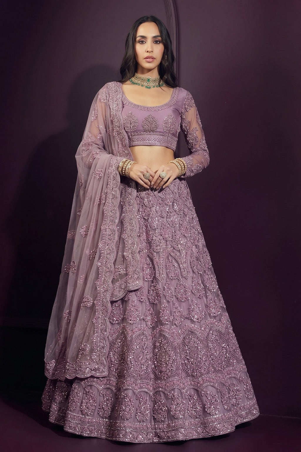Mauve reception lehenga in net with all-over hand embroidery, long-sleeve choli and sheer dupatta worn over the head and shoulder.