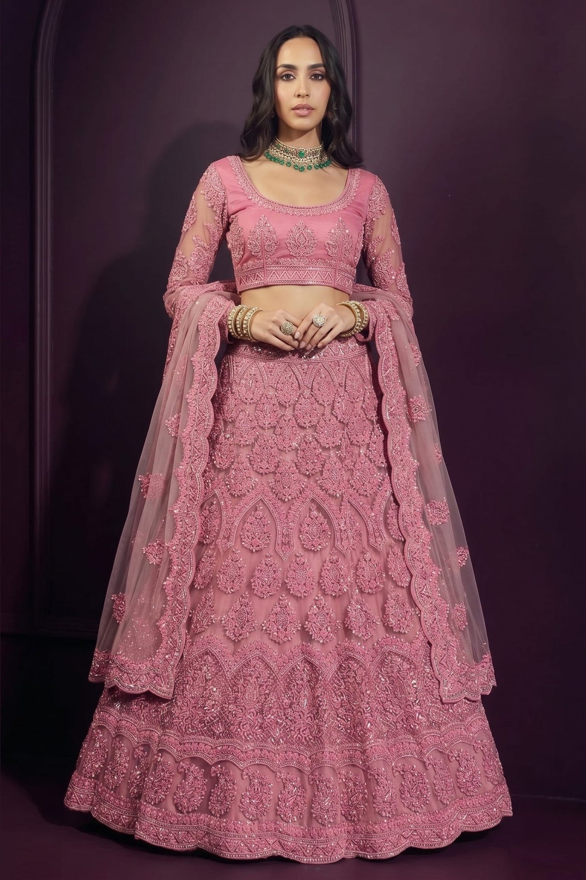 Coral pink engagement lehenga in net with hand-worked embroidery, long-sleeve blouse and dupatta draped over both shoulders.