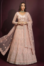 Front view of a pale peach reception lehenga with all-over hand embroidery on net, long-sleeve choli and flowing sheer dupatta.