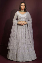Front view of a lavender grey lehenga choli for sangeet in net with hand-worked embroidery, long-sleeve choli and dupatta over one shoulder.