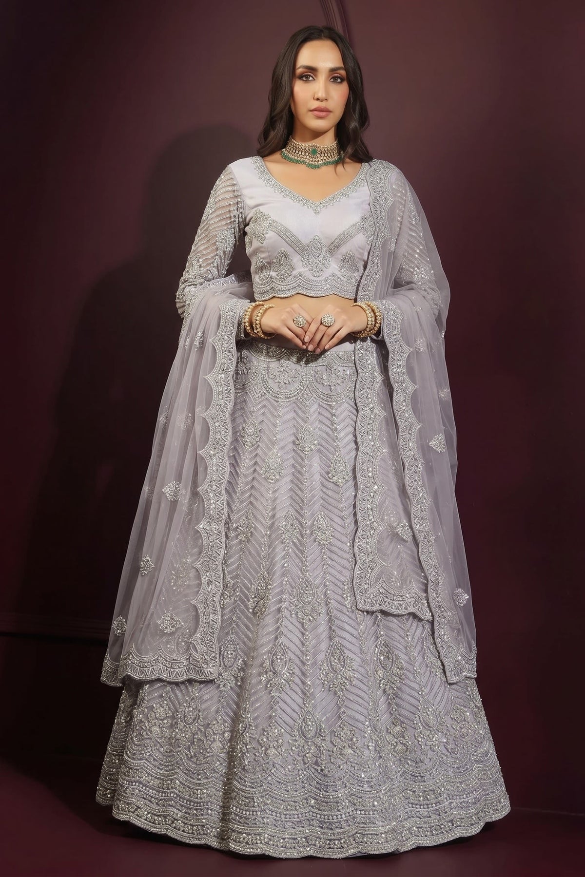 Front view of a lavender grey lehenga choli for sangeet in net with hand-worked embroidery, long-sleeve choli and dupatta over one shoulder.