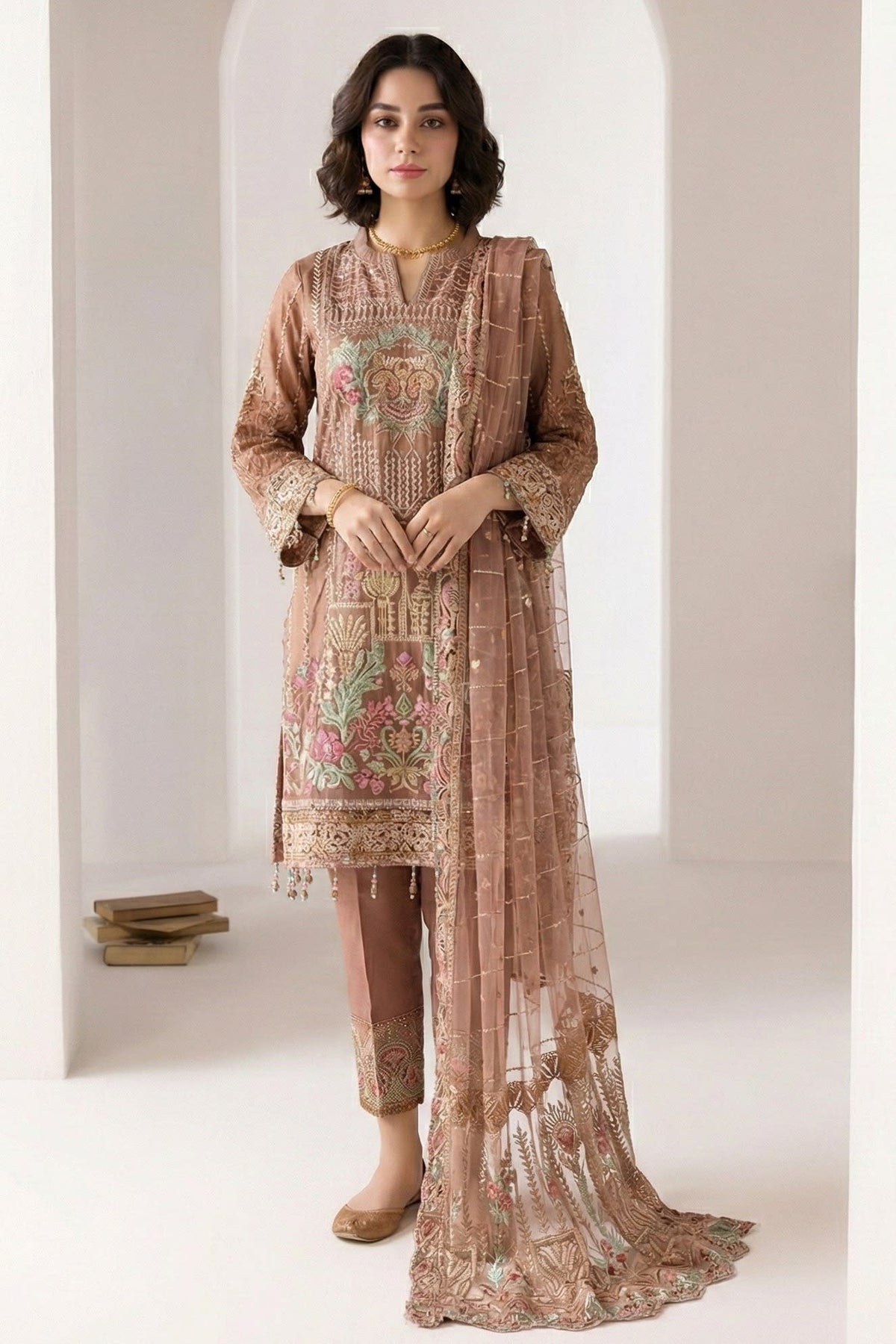 Standing model in a light brown indian kurta for women with delicate thread embroidery, straight pant with embroidered hem and sheer net dupatta.