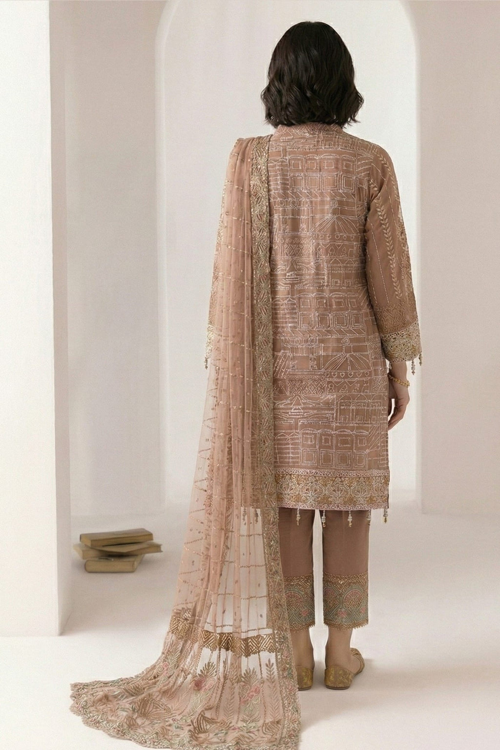 Standing front view of a light brown kurta sets design with thread embroidery on the kameez, straight pant and sheer net dupatta with embroidered edge.