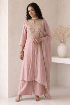 Woman wearing a pale peach women kurta set, an A-line kurta with ankle-length pants in roman silk, full-length front view.