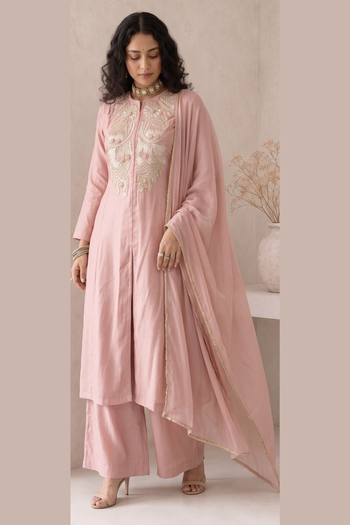 Full-length side view of a pale peach indian wedding guest dresses kurta set, an A-line kurta with ankle-length pants in roman silk.