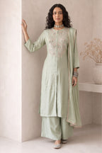 Woman wearing pastel mint green festive wear for women, an A-line kurta with ankle-length pants in roman silk, full-length front view.
