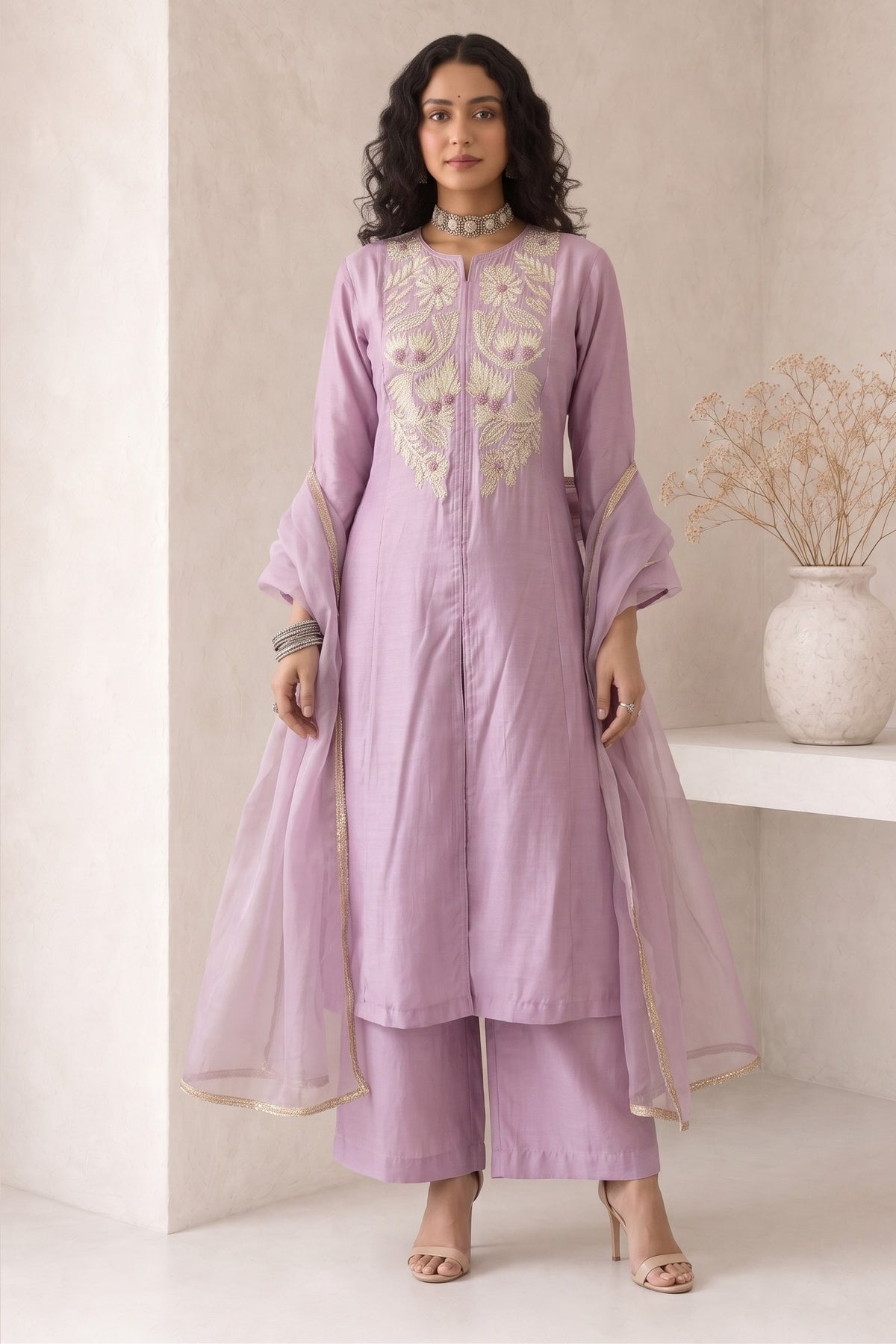 Woman wearing a pinkish lavender indian kurta set, an A-line kurta with ankle-length pants in roman silk, full-length front view.