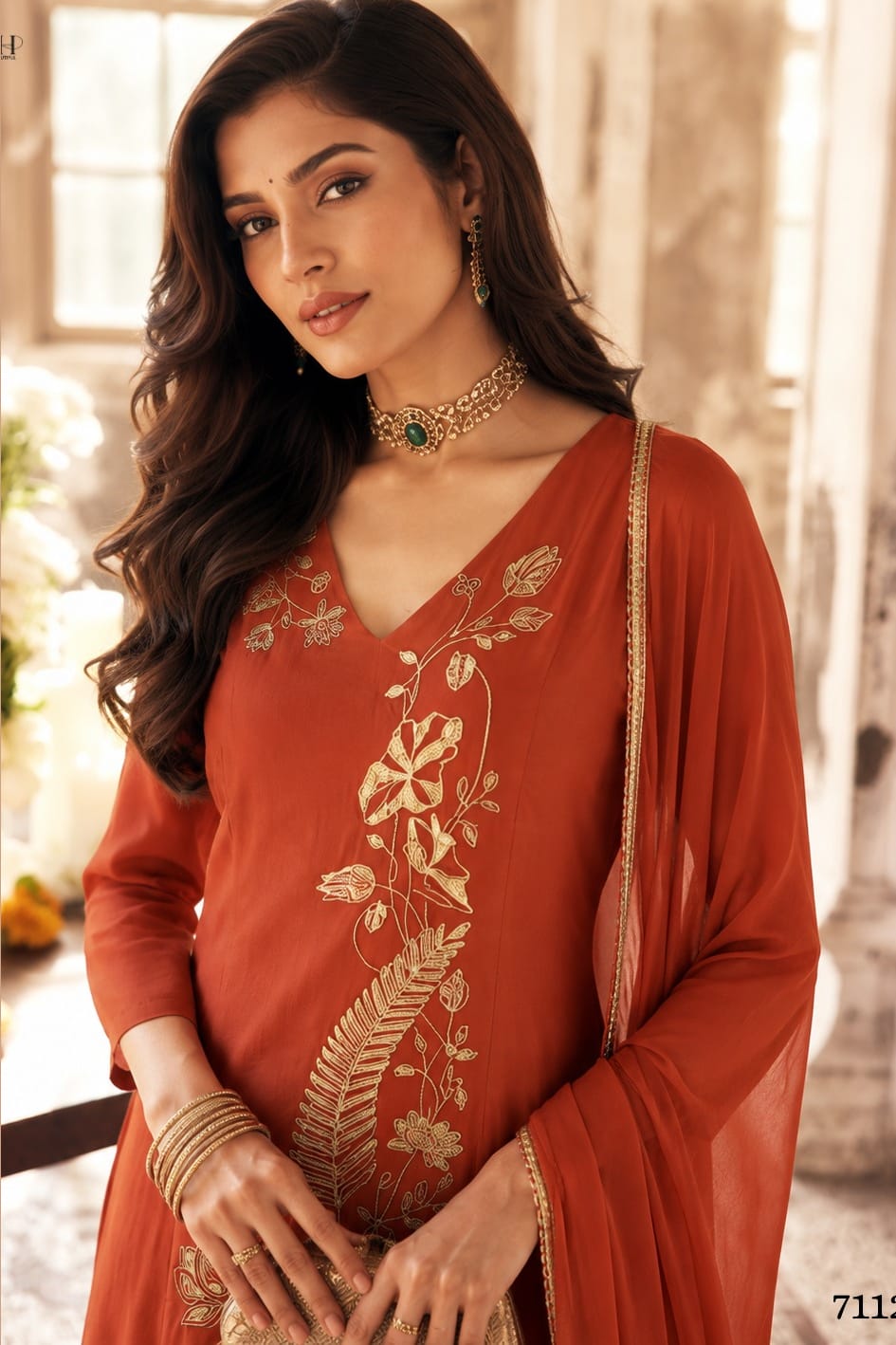 Close-up of rust indian wedding guest dresses kurta with gold zari and sequin work on the V neckline and three-quarter sleeves.